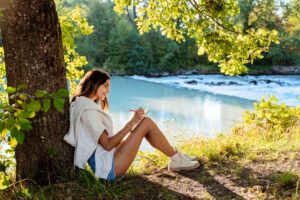 Young,Woman,Writing,And,Drawing,In,Notebook,Sitting,Under,The